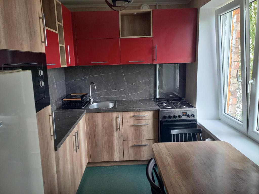 a small kitchen with red cabinets and a sink at Kandavas Street City Center Apartment in Daugavpils