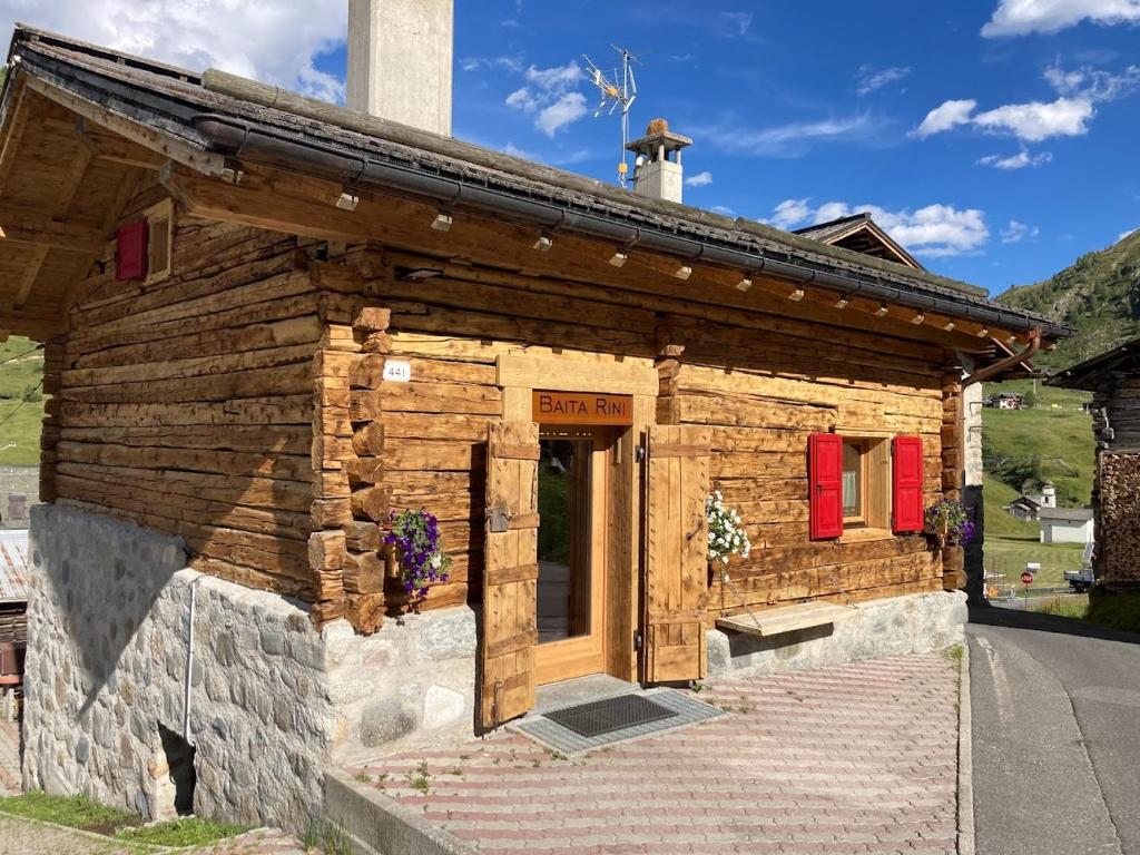 a small wooden building with red doors and windows at Baita Rini in Livigno
