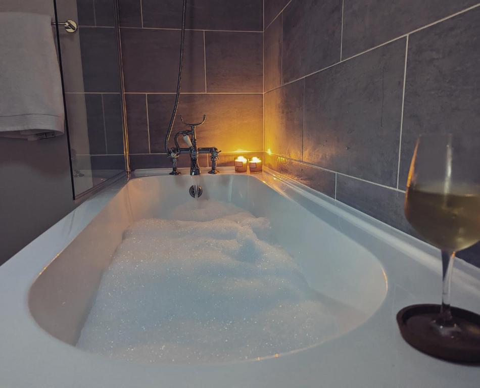 a bath tub with a glass of wine next to it at Bryngwalia Fach in Cribyn