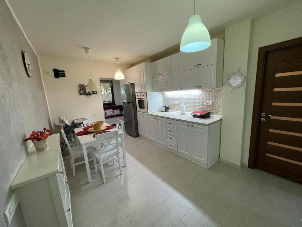 コンスタンツァにあるHoliday Apartmentの白いキャビネット、テーブルと椅子付きのキッチンが備わります。