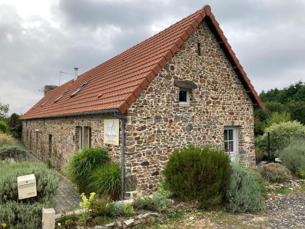 ein altes Steingebäude mit rotem Dach in der Unterkunft Cottage des Mézières in Saint-Germain-sur-Ay