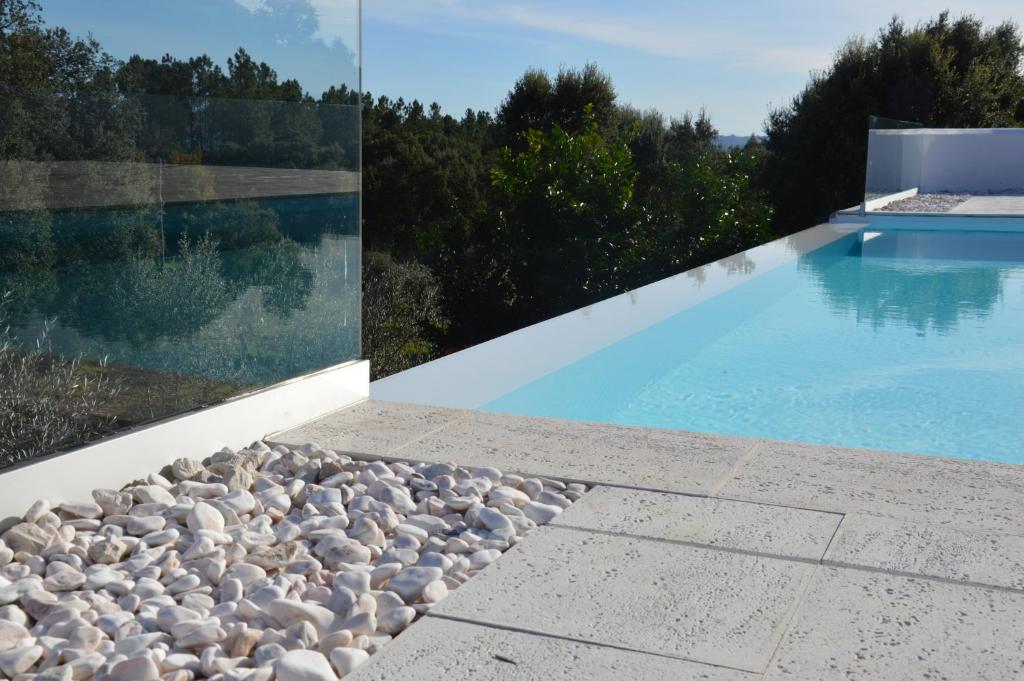 a pool with rocks next to a house at Ouzenda do Zêzere in Pedrógão Grande