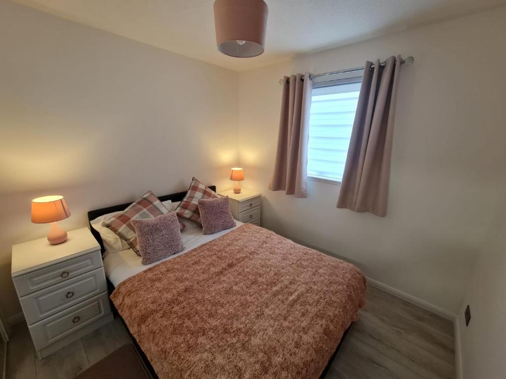 een slaapkamer met een bed met 2 lampen en een raam bij Lovely 2 bedroom flat in nice Inversness area. in Inverness