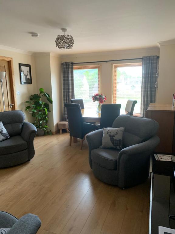 uma sala de estar com sofás, uma mesa e cadeiras em No 52 - Apartment with Lounge and Dining Area - No kitchen em Ullapool