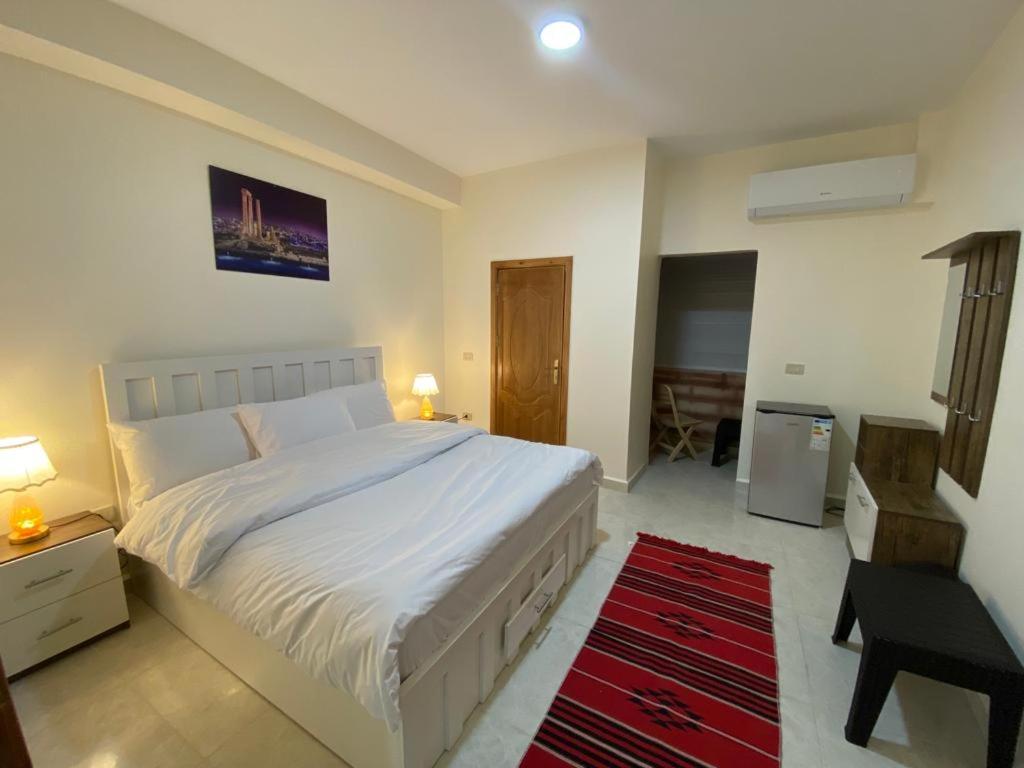a bedroom with a white bed and a red rug at Rose city inn in Wadi Musa