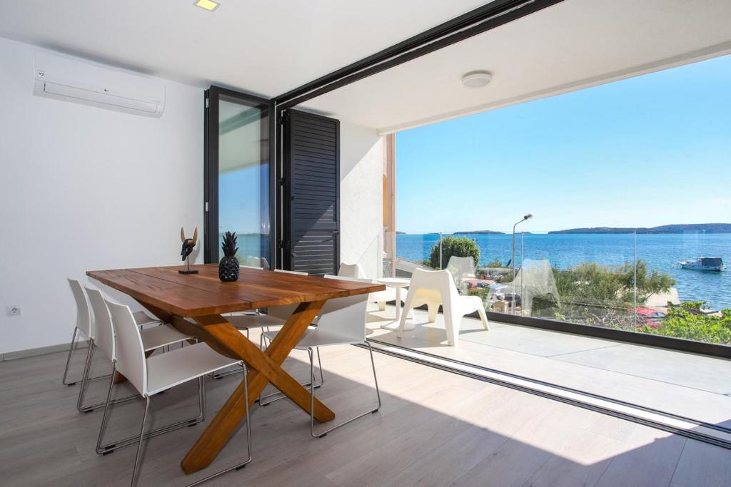 comedor con mesa de madera y vistas al océano en Villa Broda en Brodarica