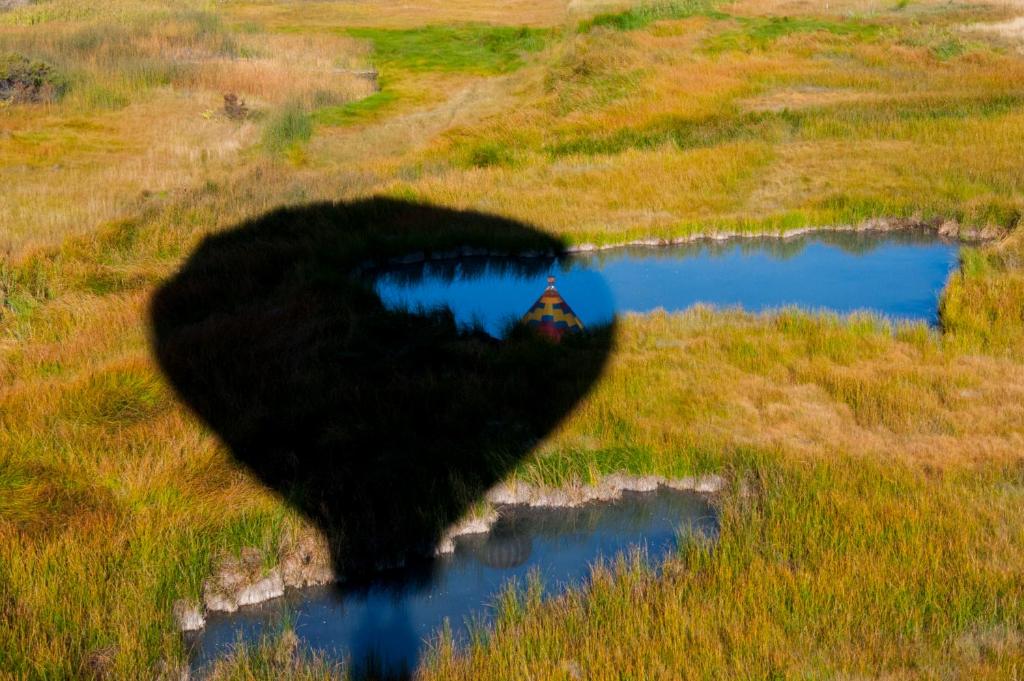 a shadow of a house in a field next to a pond at Alpine Inn in Pagosa Springs