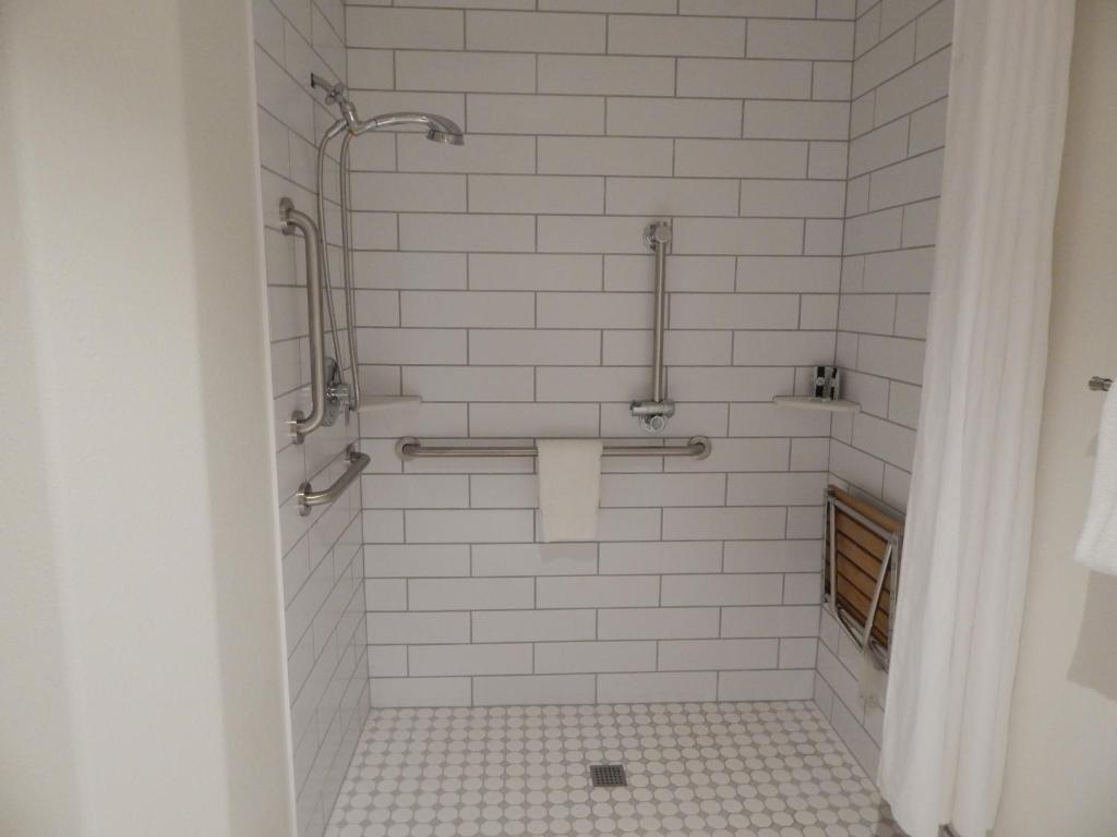 a bathroom with a shower with white tiles at Alpine Inn in Pagosa Springs