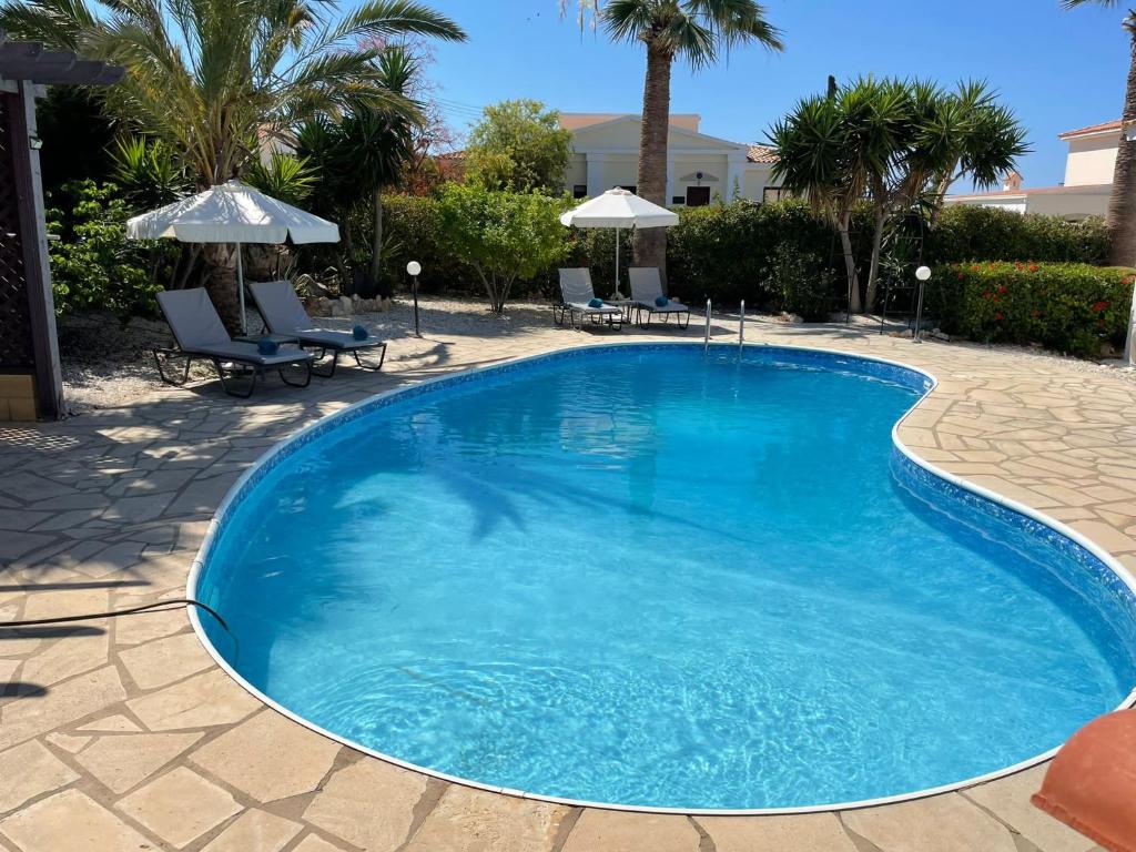 派亞的住宿－Villa Ambios，一个带椅子和遮阳伞的大型蓝色游泳池