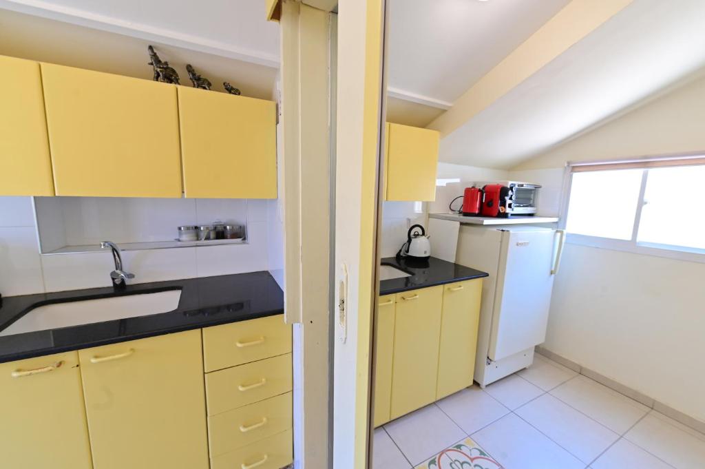 a kitchen with yellow cabinets and a white refrigerator at Sweet Home, Only 7 Min to the beach - By SEAELO EILAT in Eilat