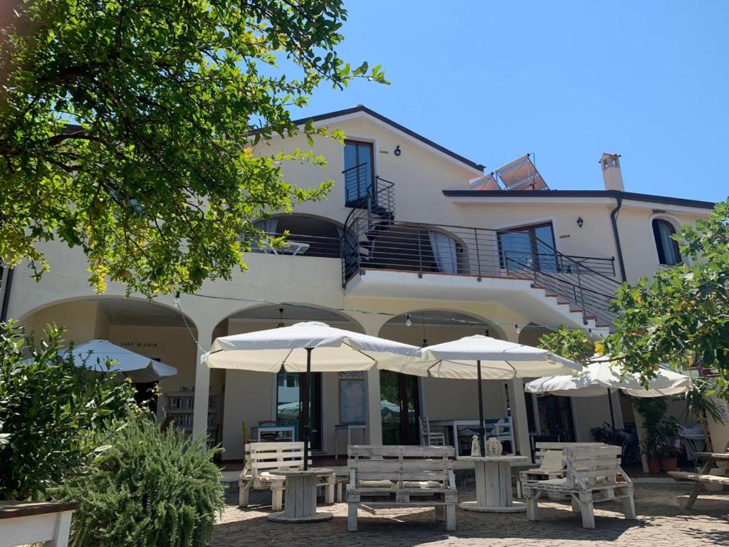 budynek ze stołami i parasolami przed nim w obiekcie Casa di Livia w mieście SantʼAnna Arresi