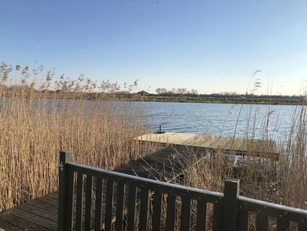 ein Dock auf einem Wasserkörper mit hoher Grasfläche in der Unterkunft Ferien am Wasser in Babberich