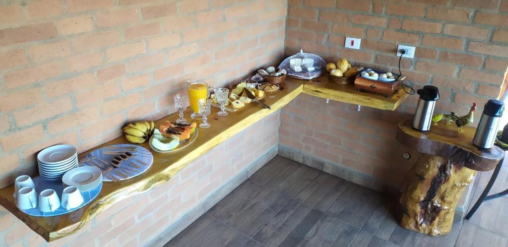 a counter with plates of food on a brick wall at Hospedaria Sol & Lua in São Bento do Sapucaí