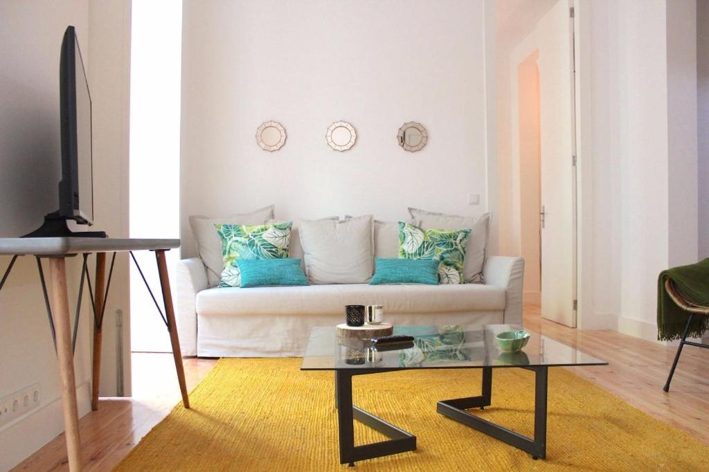 uma sala de estar com um sofá branco e uma mesa em Lisbon Coral Apartment em Lisboa