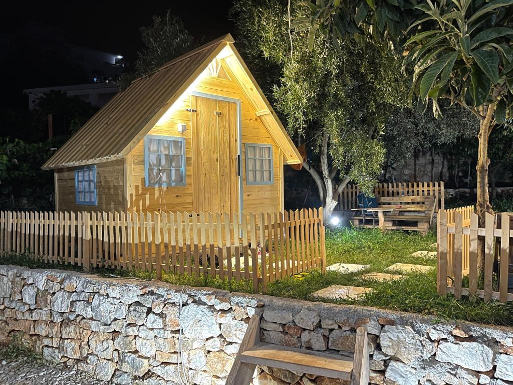 Cabaña de madera pequeña con valla y banco en Camping Albania-Secret Village Den, en Sarandë