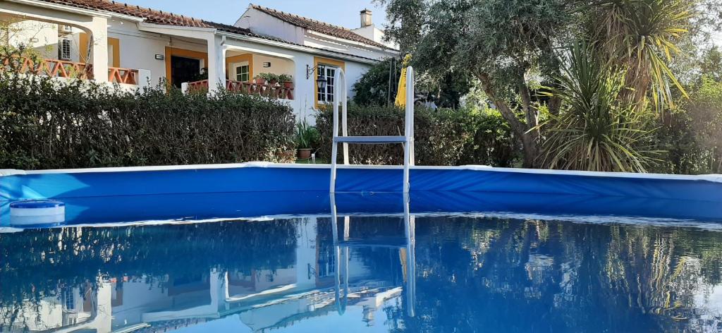 a house with a blue pool in front of a house at Casa das 3 Palmeiras in Arraiolos