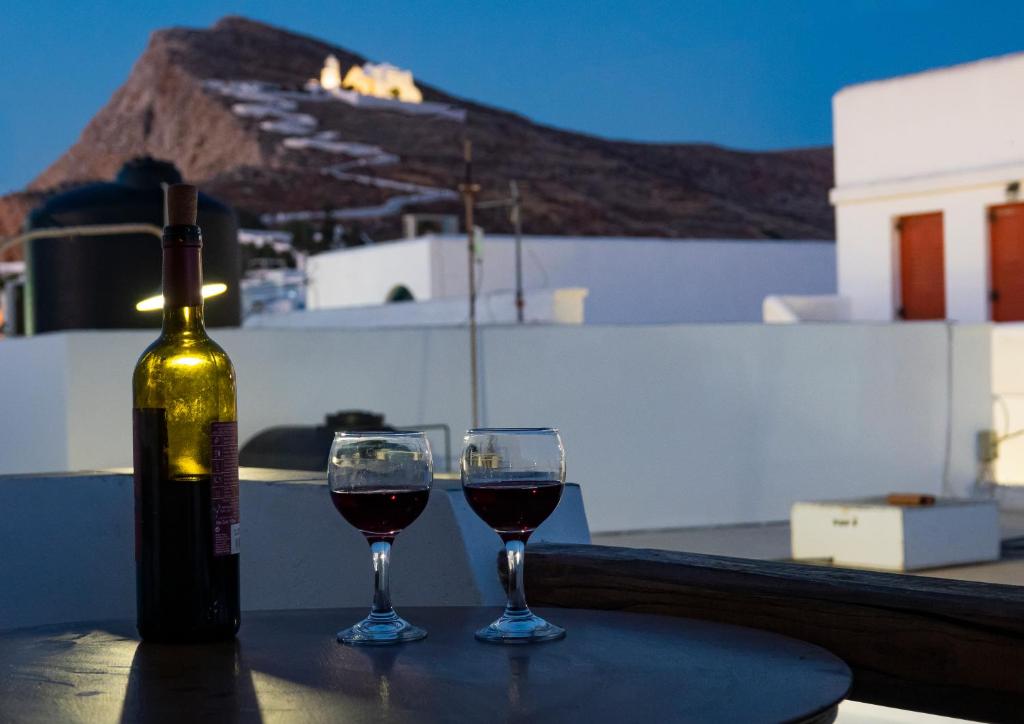 butelkę wina i dwa kieliszki na stole w obiekcie ASPRO house w mieście Chora Folegandros