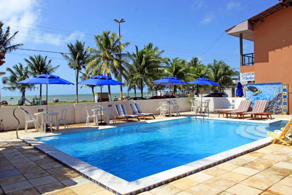 a swimming pool with chairs and umbrellas on a resort at Pousada Mariluz in Maragogi