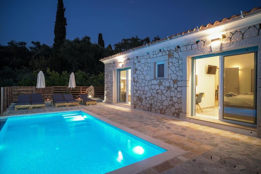 a swimming pool in front of a house at night at Villa di pietra II in Liapades