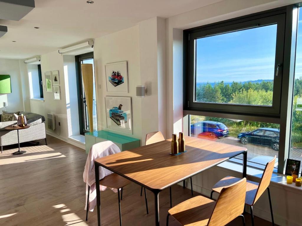 a dining room with a table and a large window at Beautiful modern sea-side apartment in the city in Edinburgh