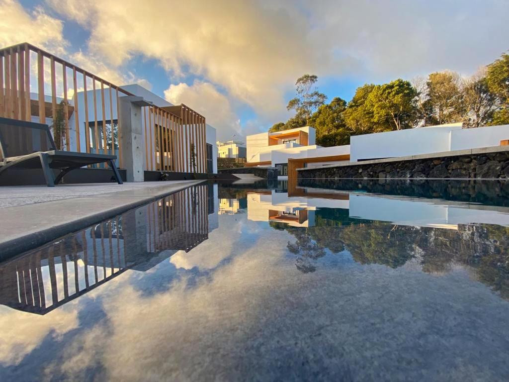 a building with a reflection in a pool of water at Vilas do Olival in Ponta Delgada