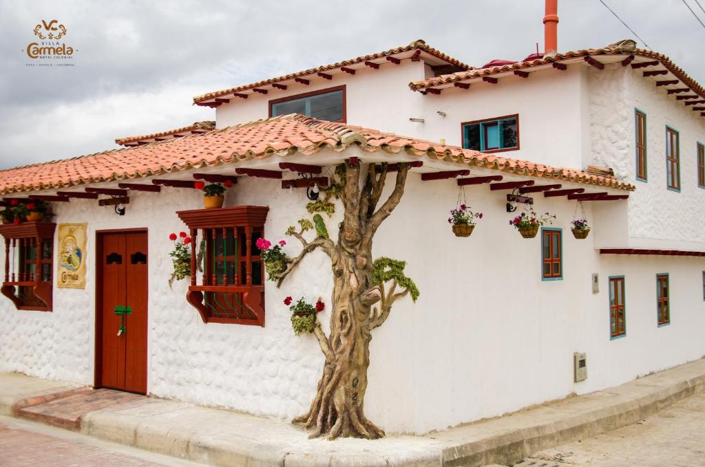 a white house with a tree in front of it at HOTEL COLONIAL VILLA CARMELA in Tota