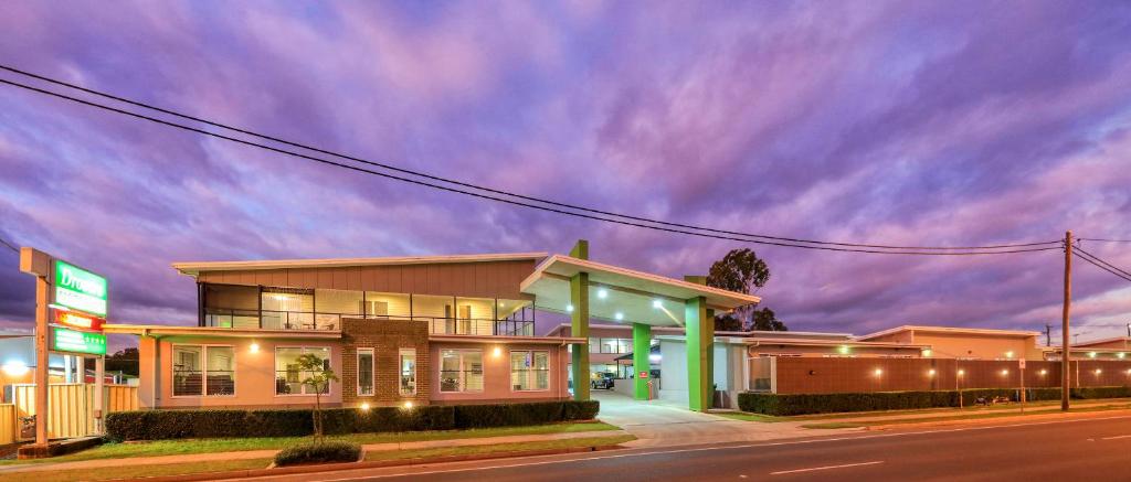 a building on a street with a cloudy sky at Drovers Motor Inn in Dalby