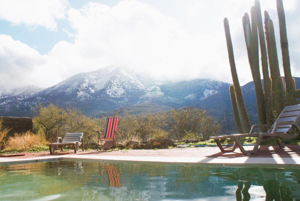 een zwembad met twee stoelen en een berg bij Ladera Encanto in Caleu