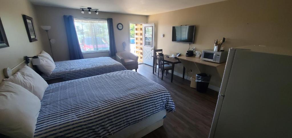 a hotel room with a bed and a desk and a window at Fair Isle Motel & The Nest in Whycocomagh