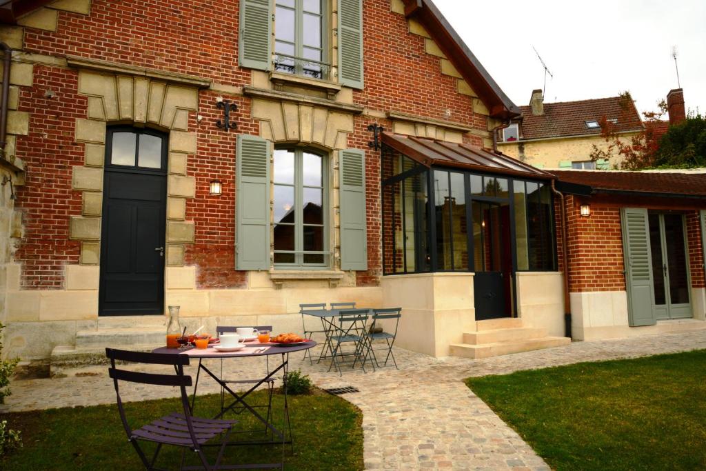 a patio with a table and chairs in front of a house at Fab House - Les Maisons Fabuleuses in Senlis