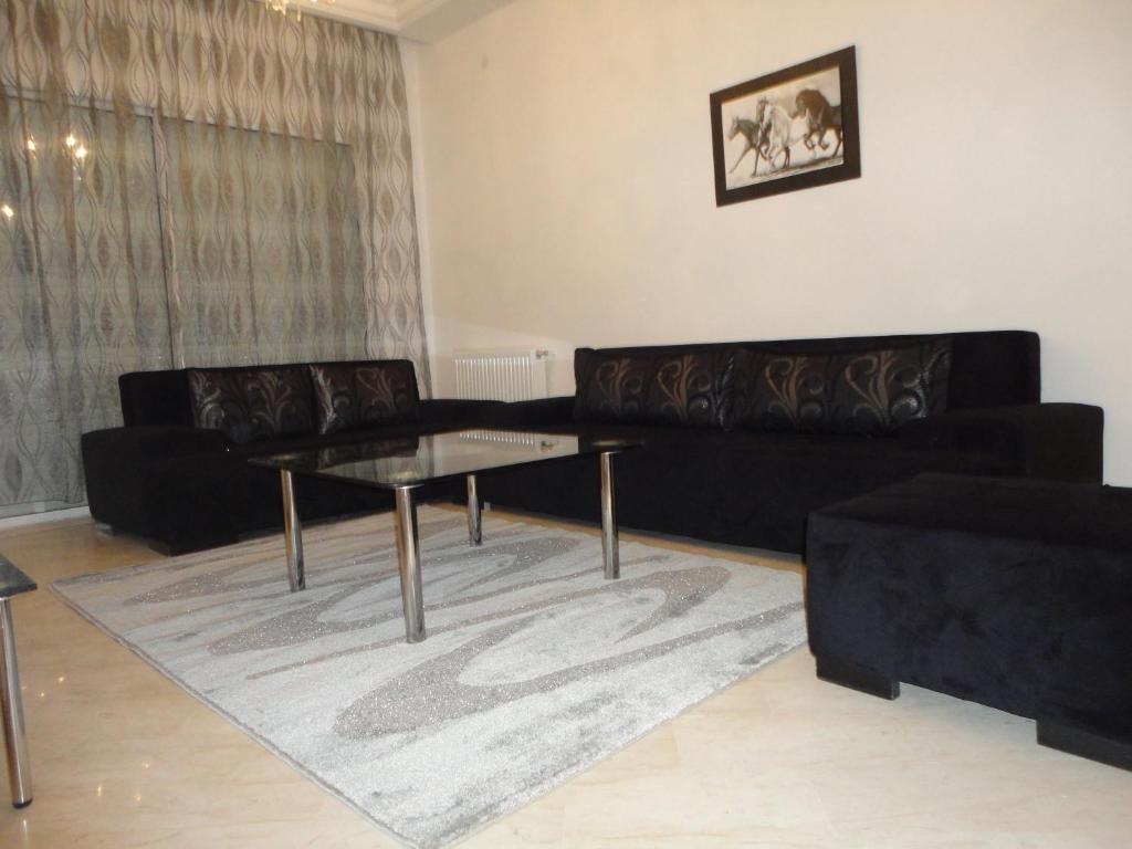 a living room with a black couch and a glass table at Appartement LaVie in Tunis