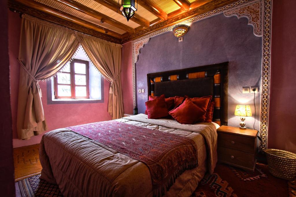 a bedroom with a bed with purple walls and a window at Gîte Atlas Mazik in Imlil