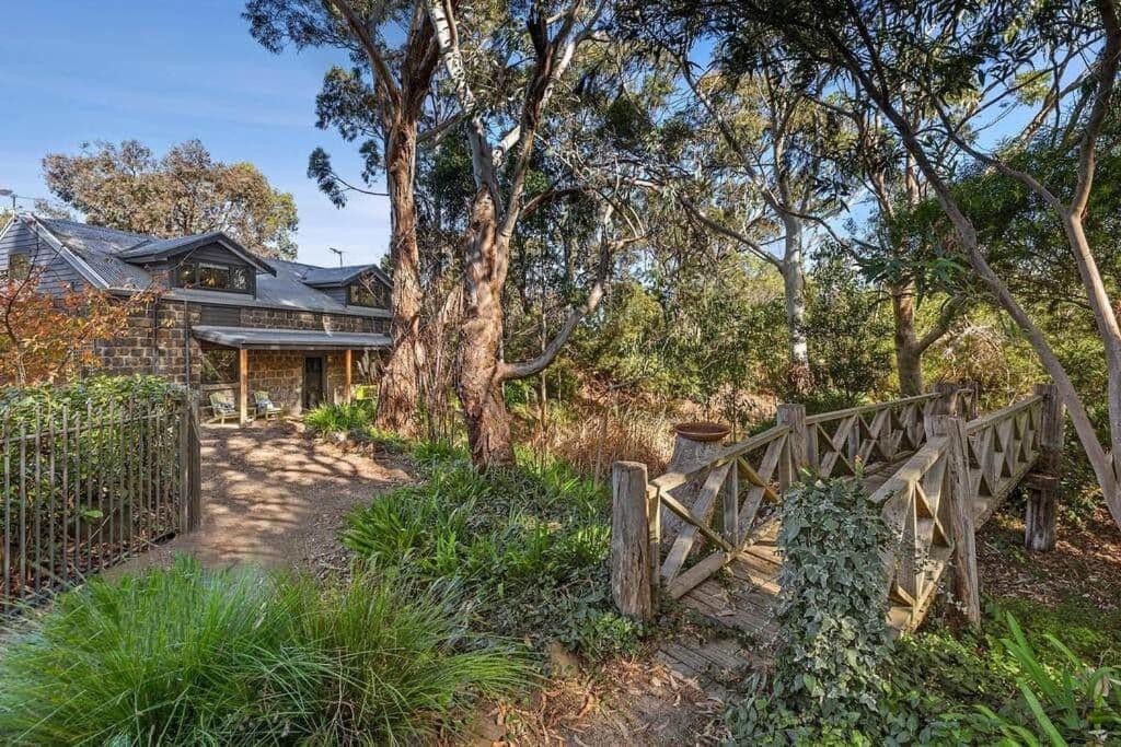 a house with a wooden fence in front of a tree at Woodlands Retreat in Ocean Grove