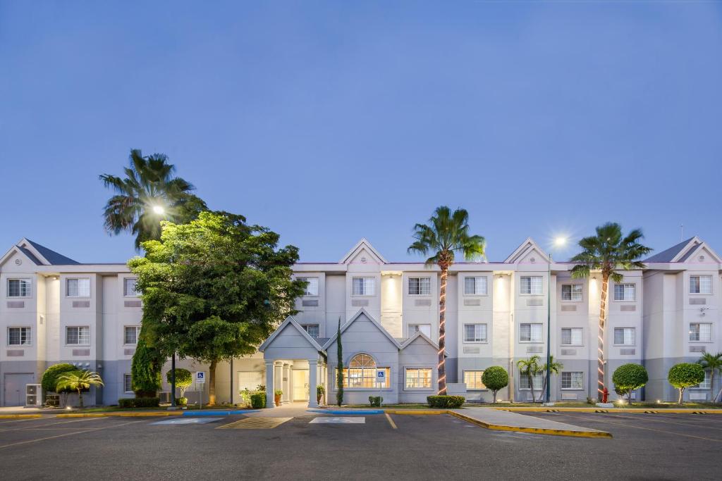 un grand bâtiment blanc avec des palmiers devant lui dans l'établissement Microtel Inn & Suites by Wyndham Culiacán, à Culiacán