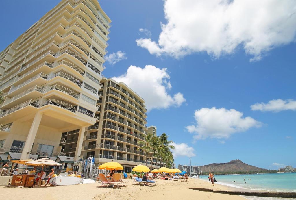 a building on a beach with umbrellas and the ocean at Castle Waikīkī Shore in Honolulu