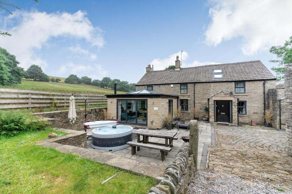 a stone house with a hot tub in the yard at Carr House Farm in Glossop