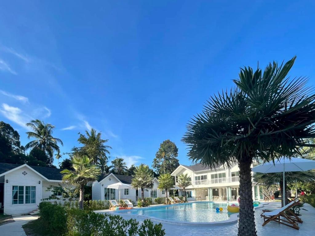 a resort pool with a palm tree in the foreground at Thirty Tree Garden House in Chumphon