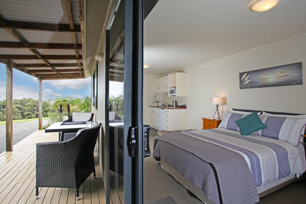 a bedroom with a bed and a desk and a balcony at Auckland Country Cottages in Clevedon