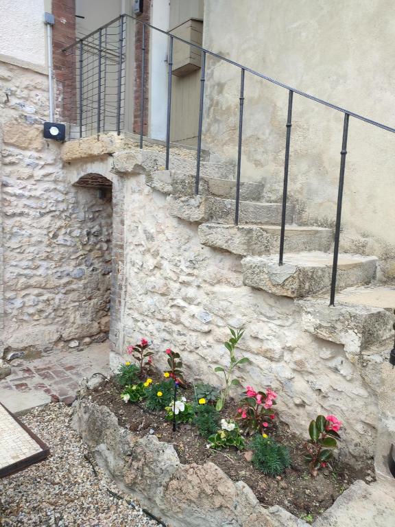 a stone building with stairs and flowers in a garden at La maison fleurie 2 in Sainte-Geneviève-lès-Gasny