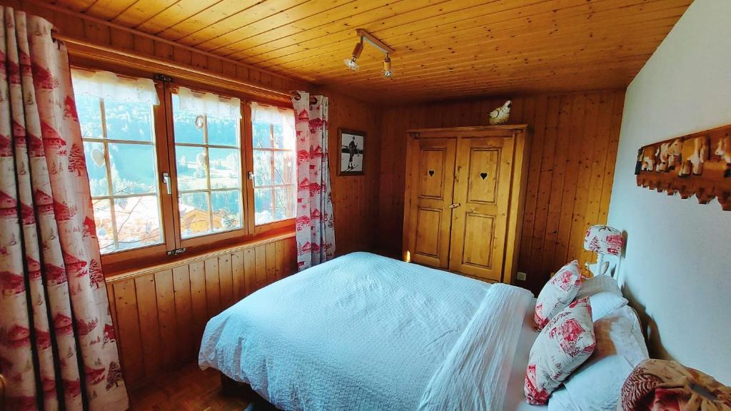 a bedroom with a bed in a cabin with windows at Waldruhe in Jaun