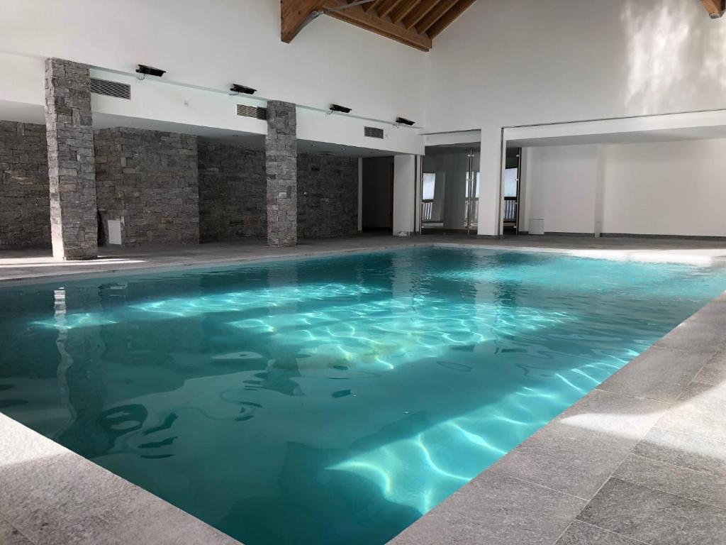 a large swimming pool with blue water in a building at residence avec piscine ,chalet des rennes in Vars
