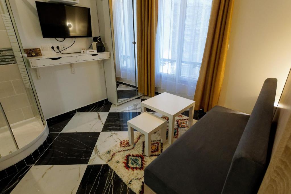 Elle comprend un petit salon doté d'un canapé et d'une télévision. dans l'établissement Paris Opéra / Galeries Lafayette : charmant studio, à Paris