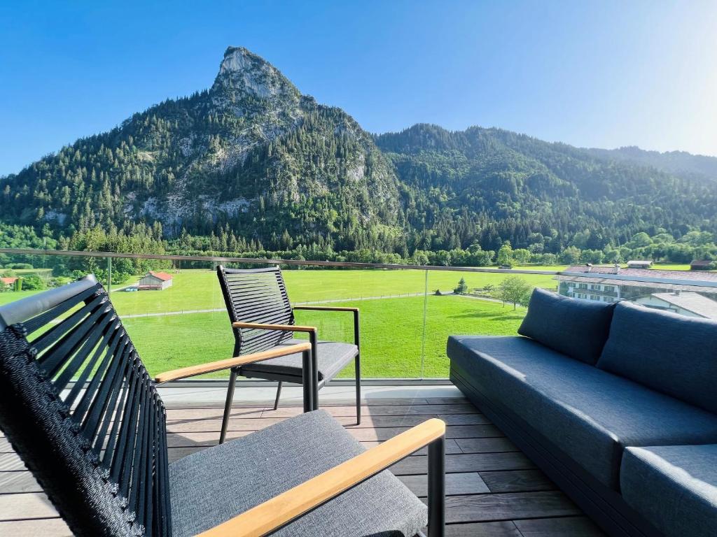 a patio with a couch and chairs and a mountain at Bergblick 1342 in Oberammergau