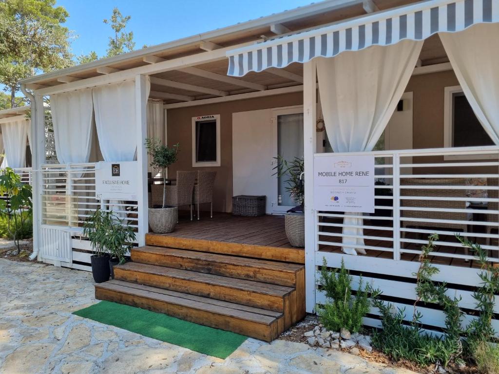 une maison avec une clôture blanche et des escaliers en bois dans l'établissement Mobile home RENE, à Biograd na Moru