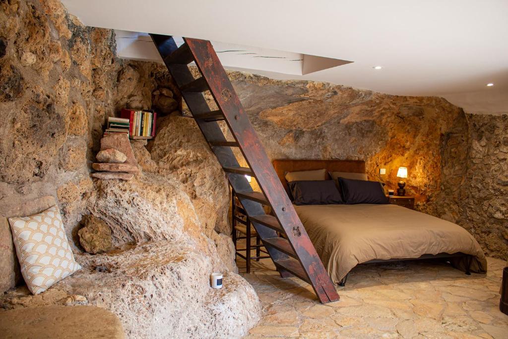 1 dormitorio en una cueva con cama y escalera en Le jardin de Camille, en Cotignac
