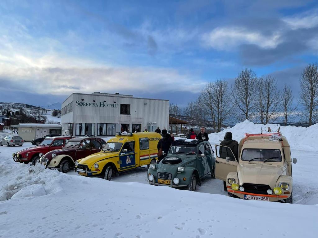 een groep auto's geparkeerd op een parkeerplaats in de sneeuw bij Sørreisa Hotell in Nordstraumen
