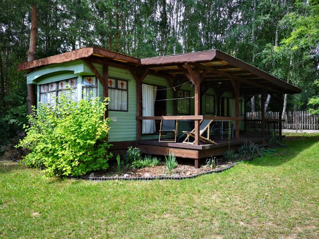 a green cabin with a table in the yard at Domki holenderskie na Mazurach in Dźwierzuty
