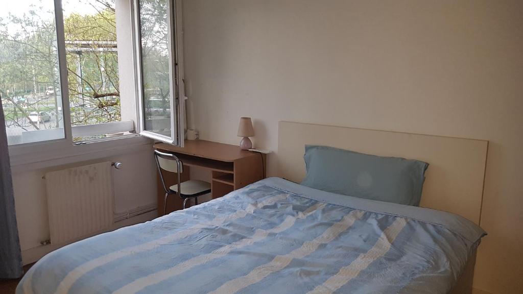 1 dormitorio con cama, escritorio y ventana en une chambre privee entre paris et disneyland, en Noisy-le-Grand