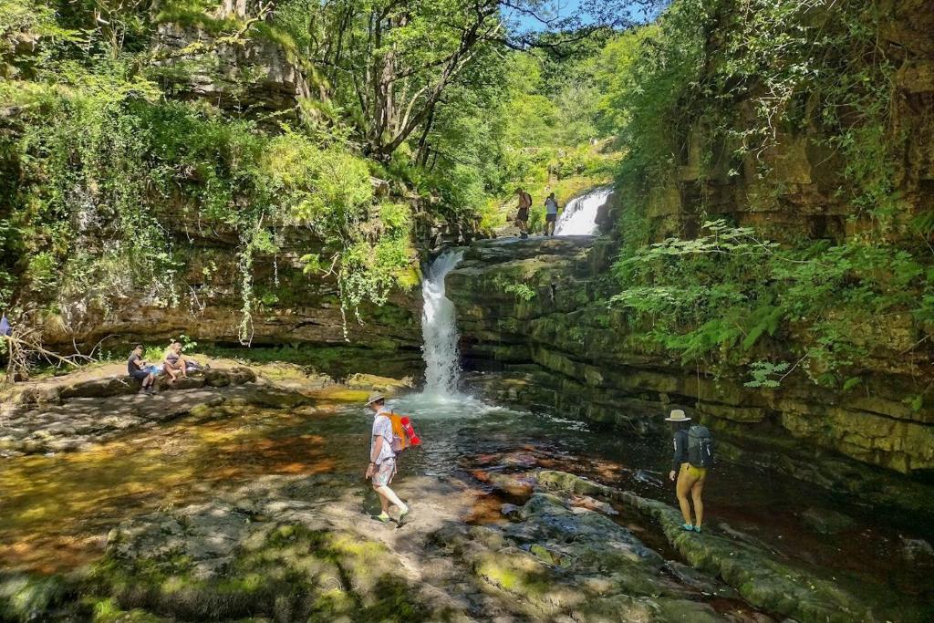 a painting of people standing in a waterfall at Waterfall Lodge in Pont-Nedd-Fechan