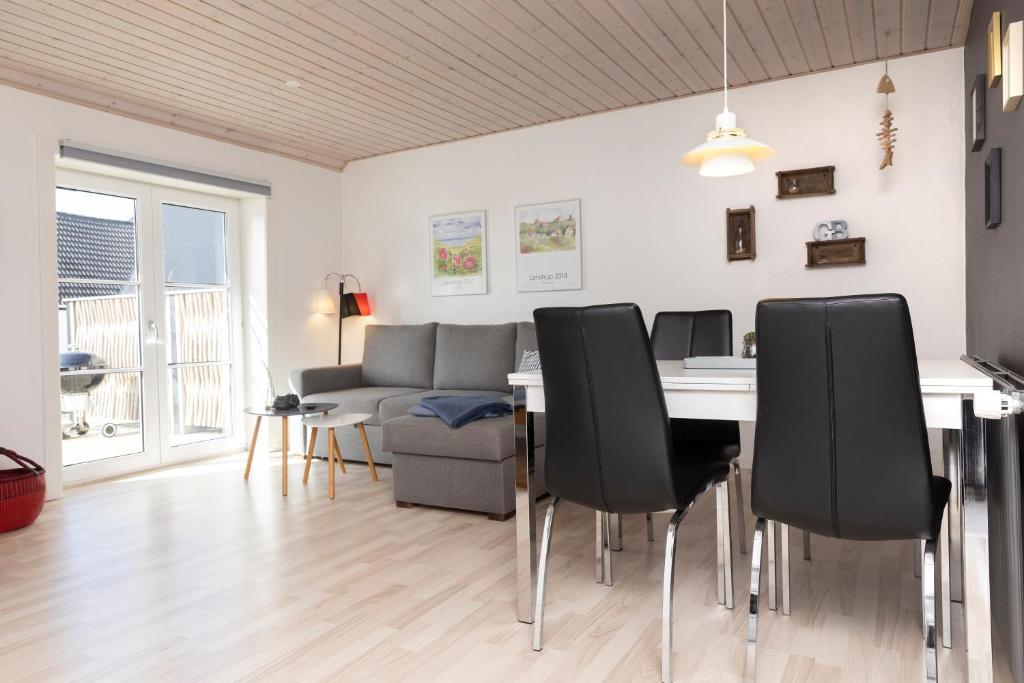 sala de estar con mesa, sillas y sofá en Havrevang, Ferielejligheder en Lønstrup